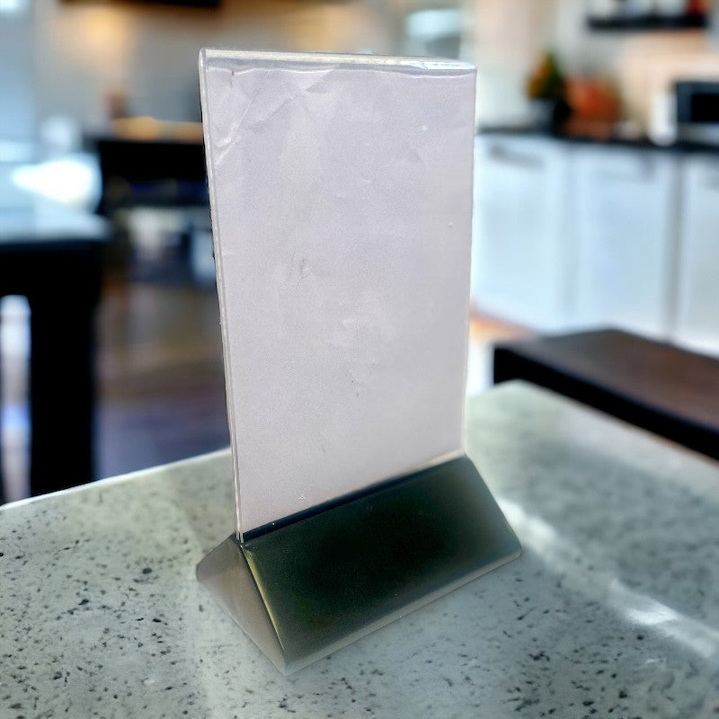 Skilteholder inkl. A6 akryl med sort plastikkfot. 10,5 x 6,5 x H 19 cm.