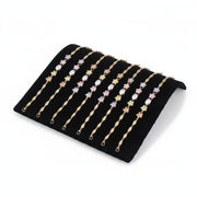 SuperSellerS black flocked curved jewelry display tray holding eight delicate gold bracelets with floral accents